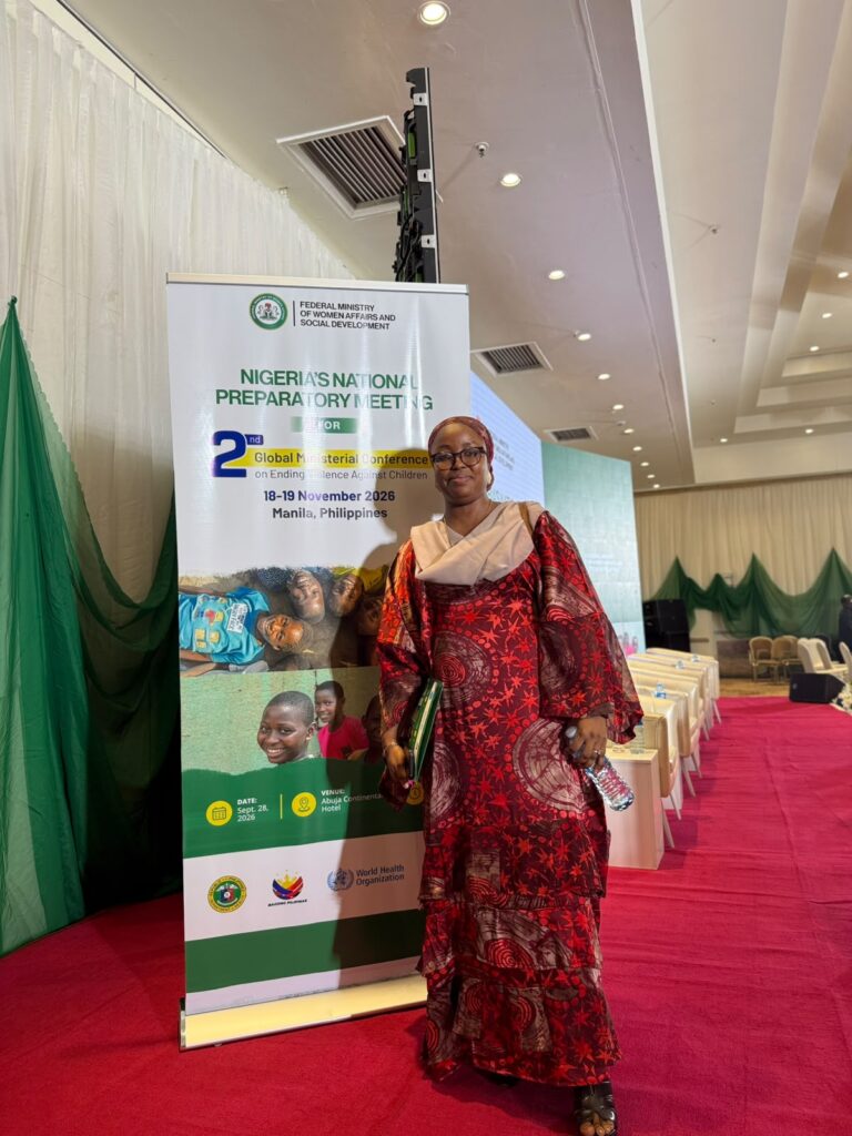 Participant beside the National Preparatory Meeting banner at the Abuja Continental Hotel