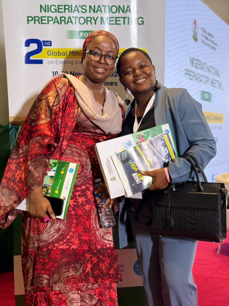 Participants with conference materials in front of the National Preparatory Meeting banner in Abuja